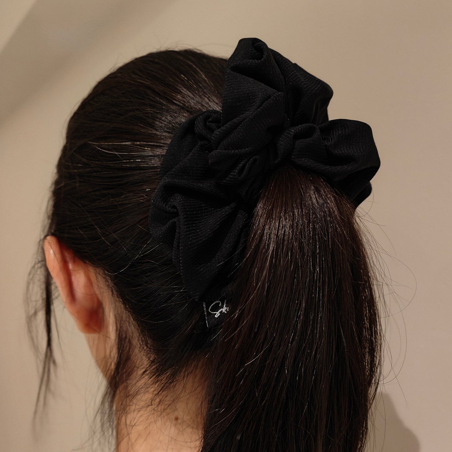 A lady tying her hair up with the Natalie Black Sheer Jersey Scrunchie