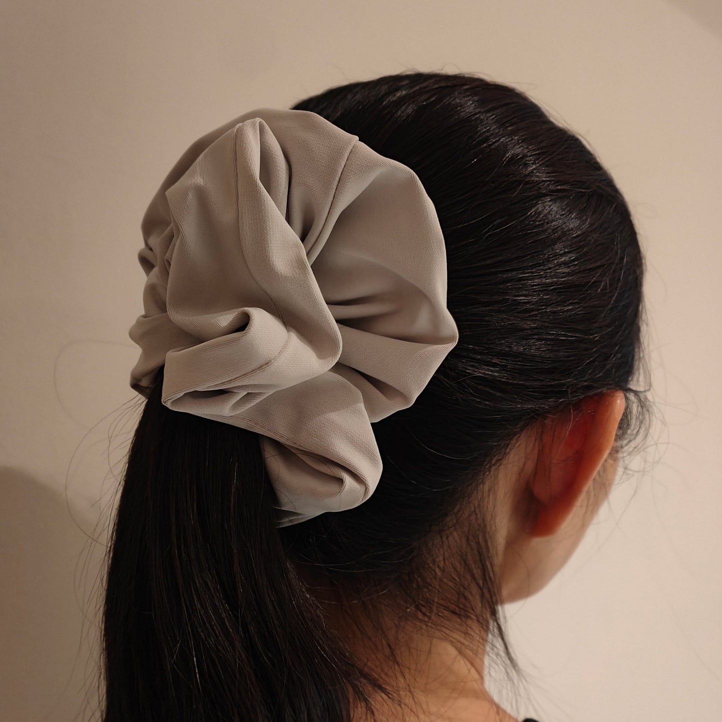 The silver Angela sports scrunchie tied around a lady's hair
