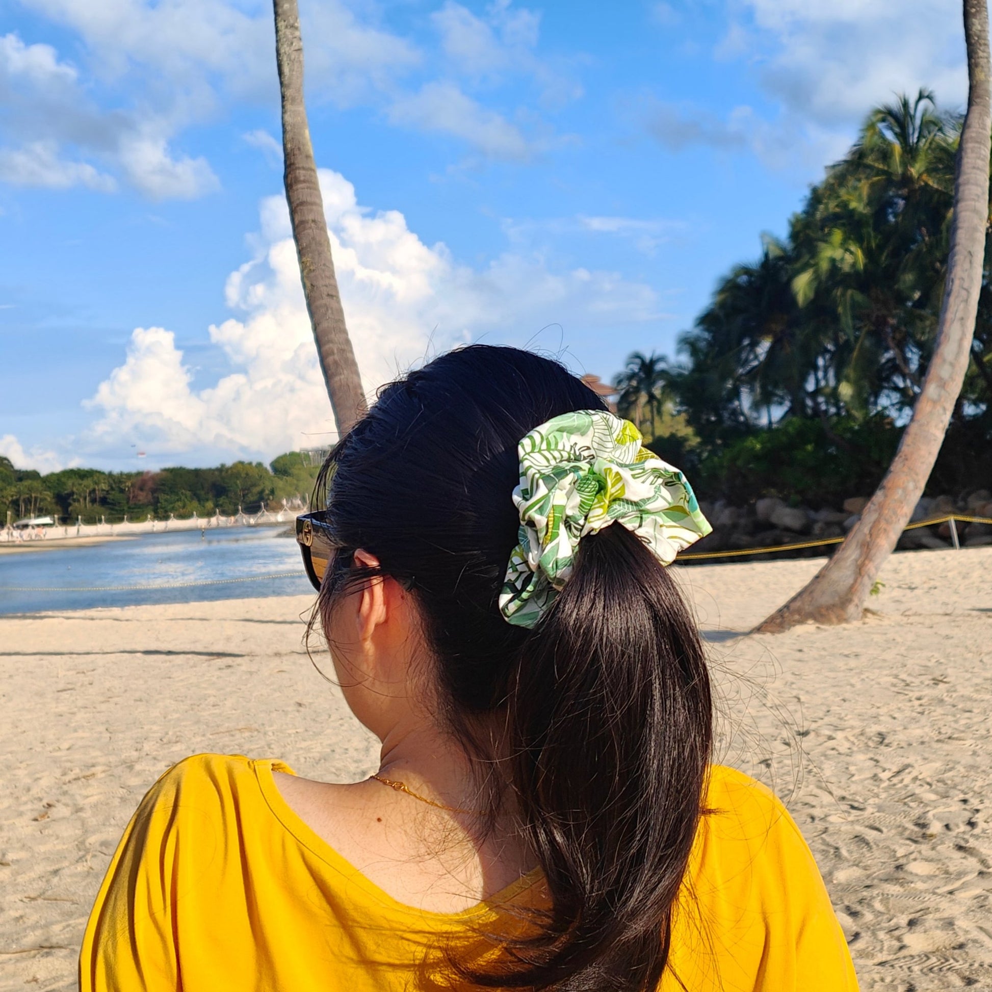 A photo of a girl tying up her hair in a ponytail with the Kimberly Scrunchie